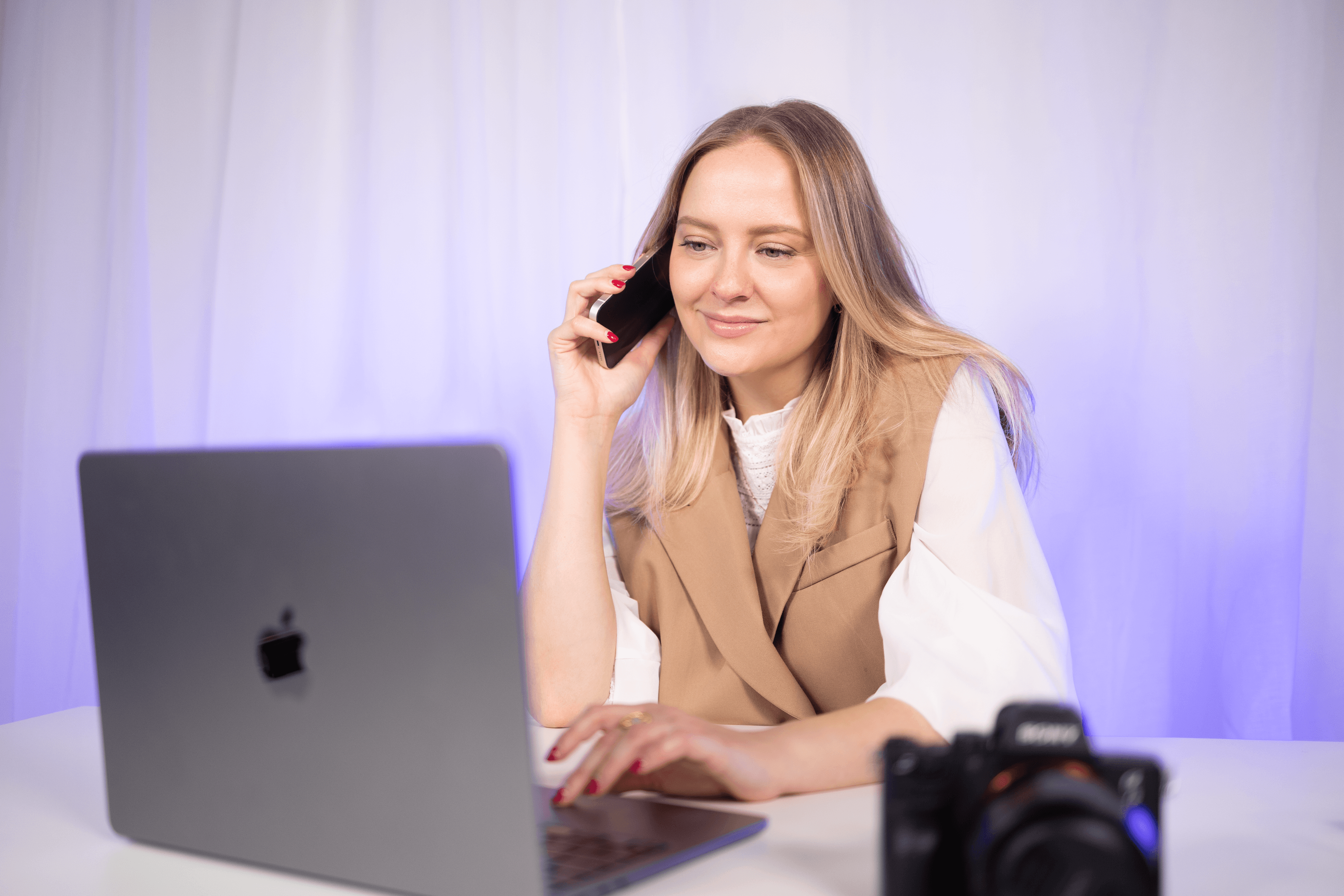 Žena kontroluje svůj telefon u pracovního stolu